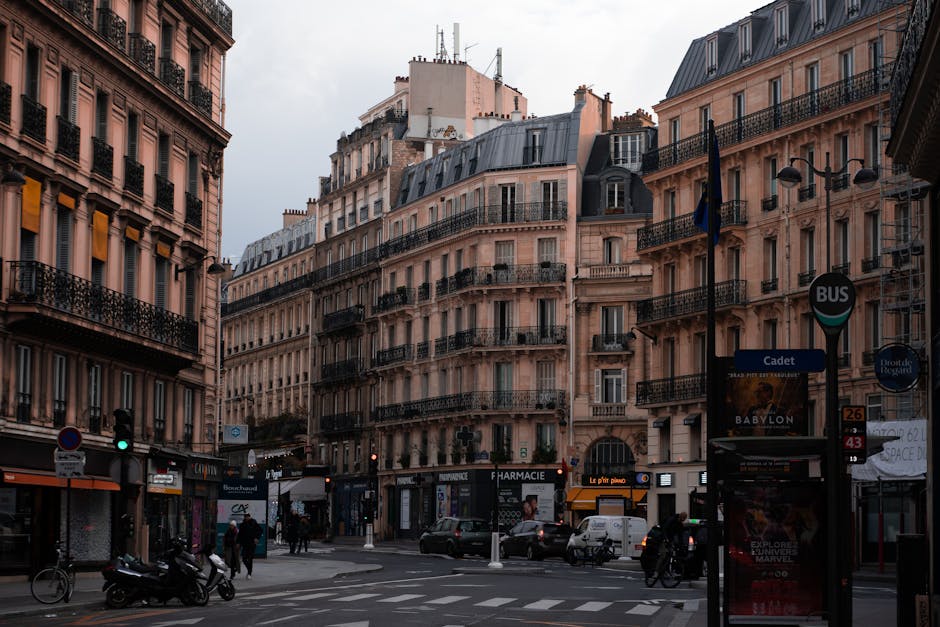 Vue d'une rue parisienne haussmannienne avec immeubles en pierre de taille et activité urbaine en arrière-plan