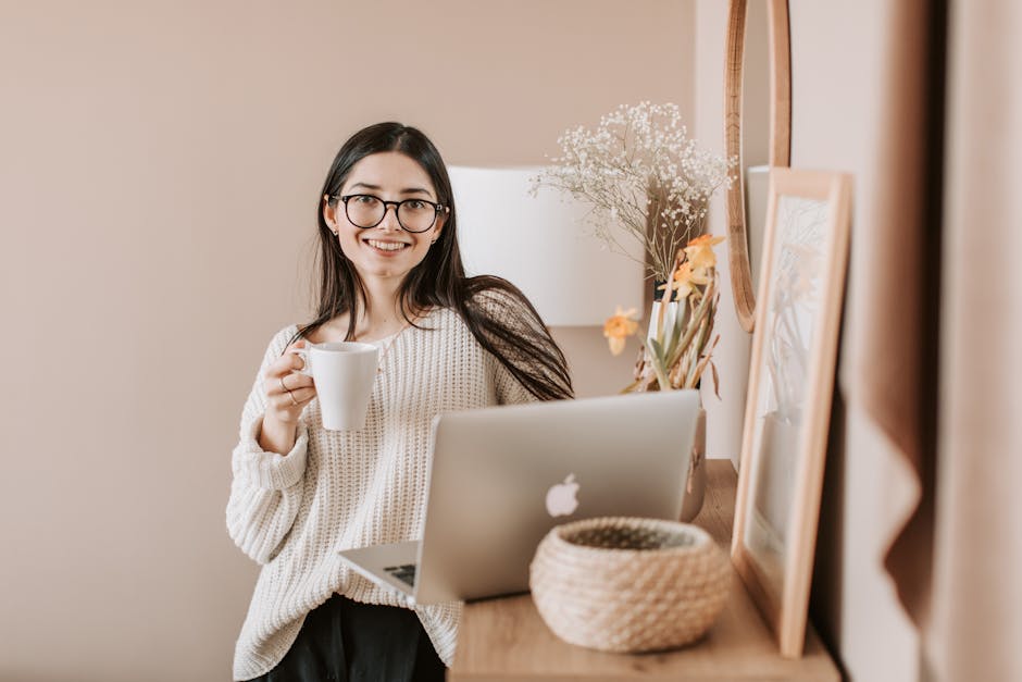 Femme souriante avec un café et un ordinateur portable, ambiance détendue à la maison